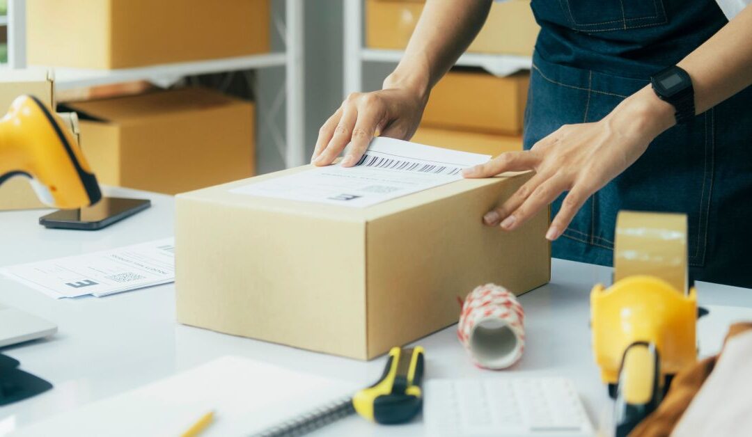 small business owner putting a shipping label on a parcel after using free shipping software