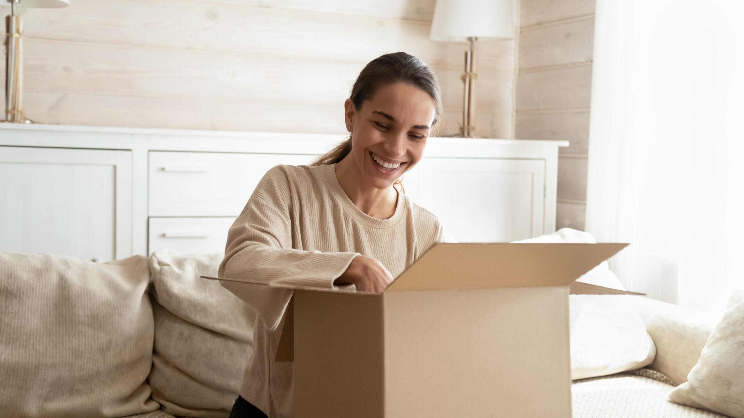 a happy woman opening a parcel containing an ecommerce order delivered via international shipping