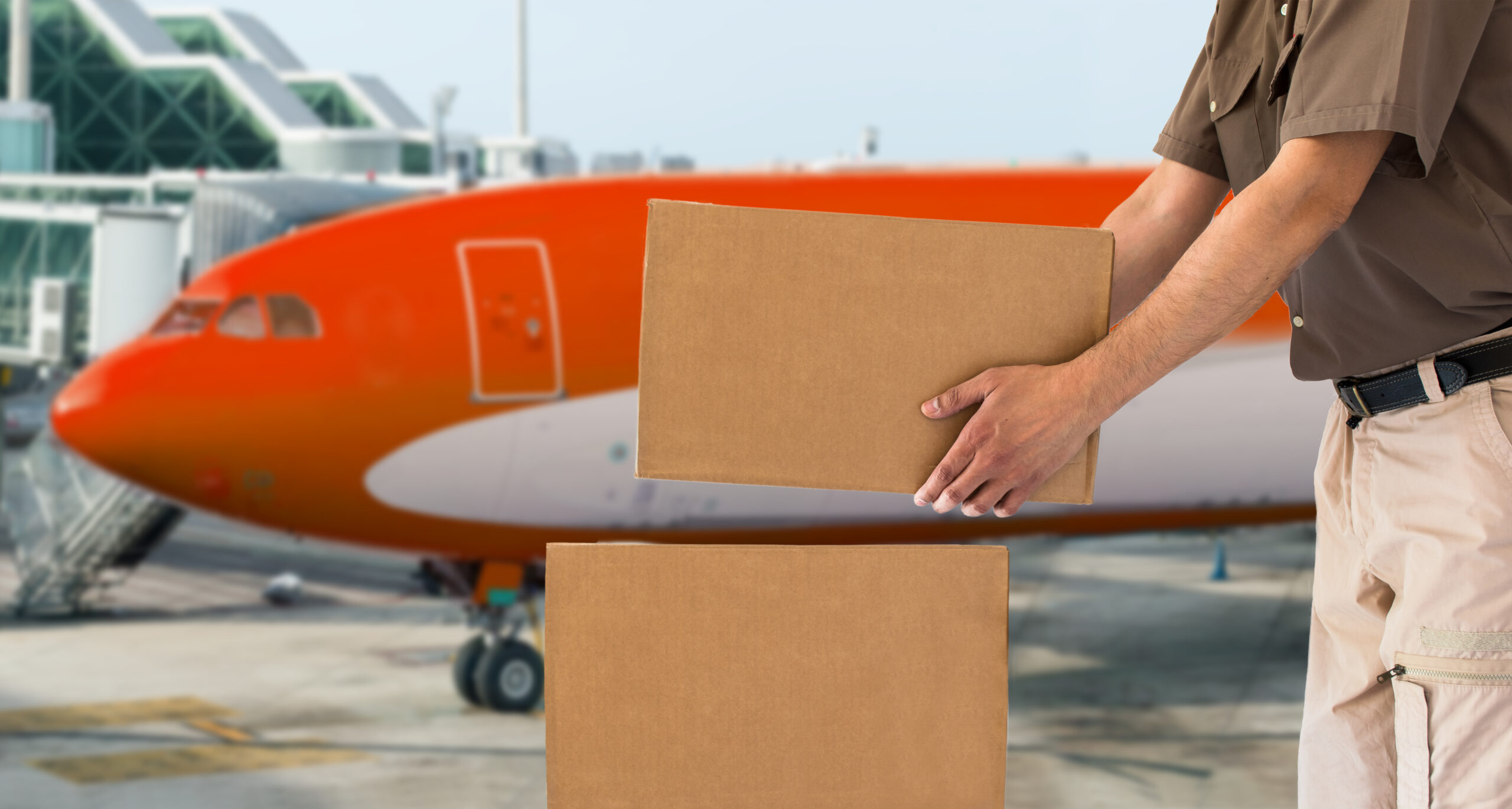 An international shipping carrier worker stacking parcels in front of an airplane