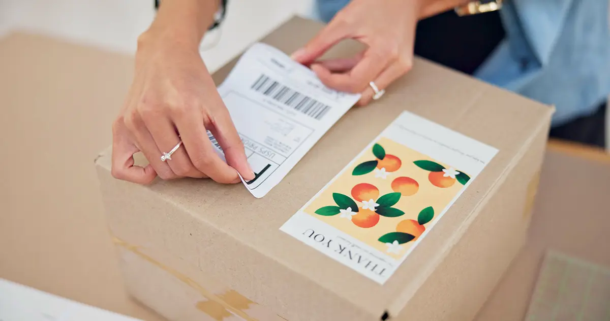 Seller applying shipping label to a parcel for best international shipping for Shopify