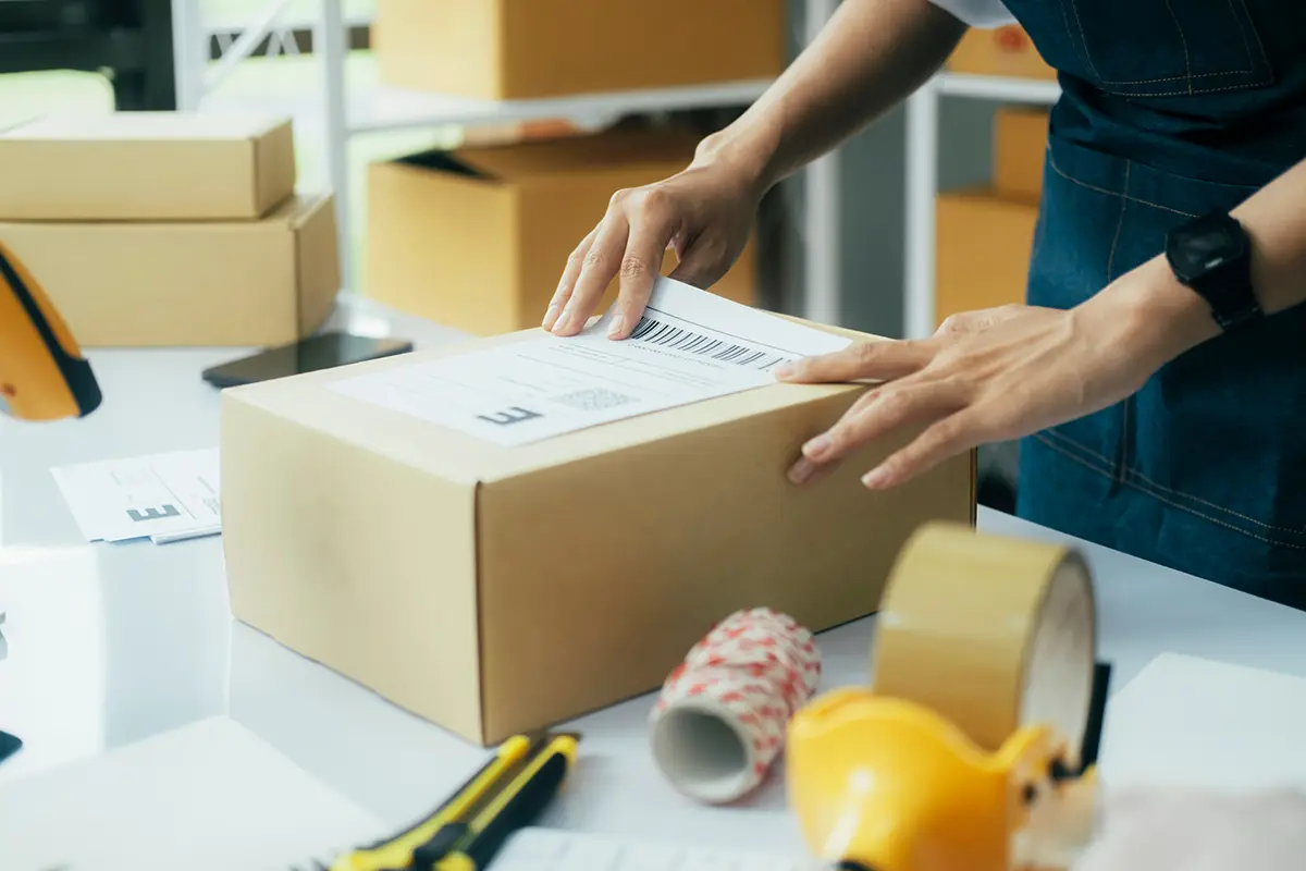 Small business owner creating shipping labels online and affixing a label to a parcel