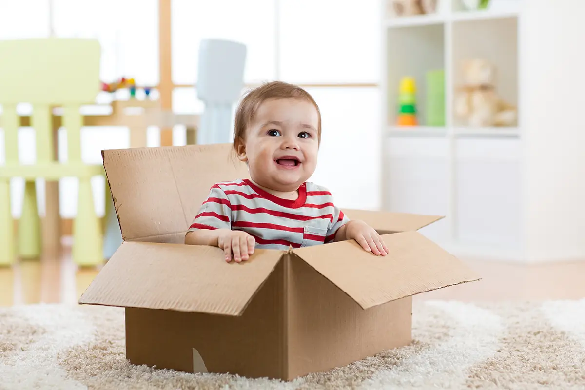 A happy baby in a cardboard box representing someone new to international shipping