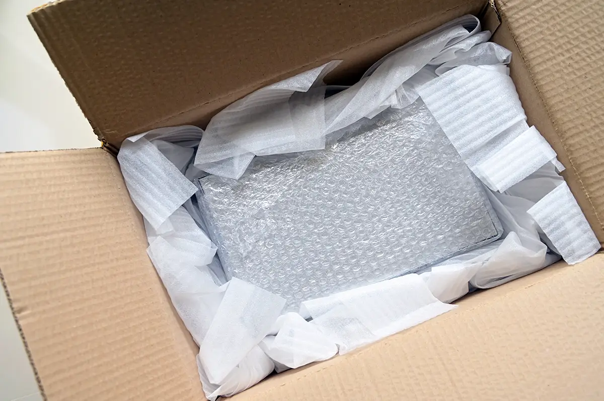 Package prepared for shipping with item wrapped in bubble wrap and foam packing material in a cardboard box