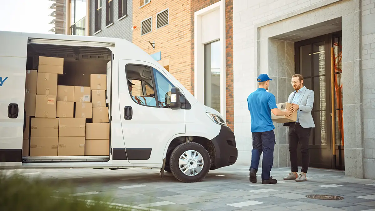 Small parcel delivery van and driver delivering a package to a businessman