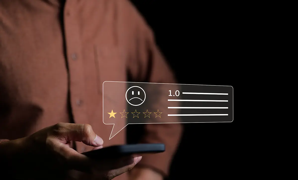 Unhappy ecommerce customer in a brown shirt leaving a 1-star negative review on a mobile device